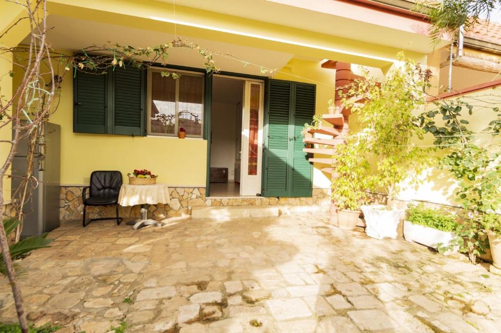 un patio di una casa con tavolo e persiane verdi di Casa vacanze Nonna Nella a Porto Cesareo