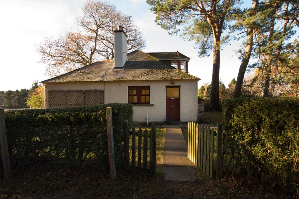 una pequeña casa blanca con una puerta y una valla en The White Cottage, en Elgin