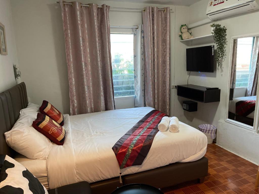 A double bed sits between a curtained window and a wall-mounted television.