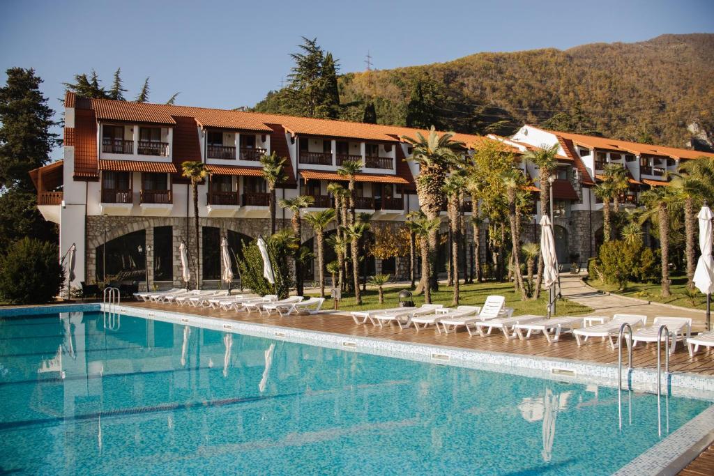 a hotel with a large swimming pool with lounge chairs at Hotel Abaata in Gagra