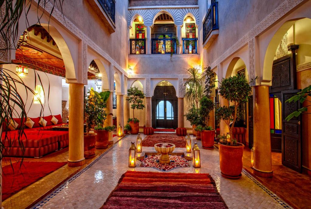 a lobby with a large room with red furniture and plants at Riad Basim in Marrakesh