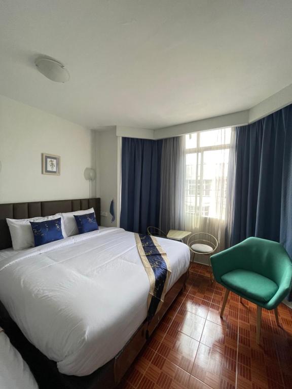 曼谷的住宿－Acozyposhtel，一间卧室配有一张大床和一张绿色椅子