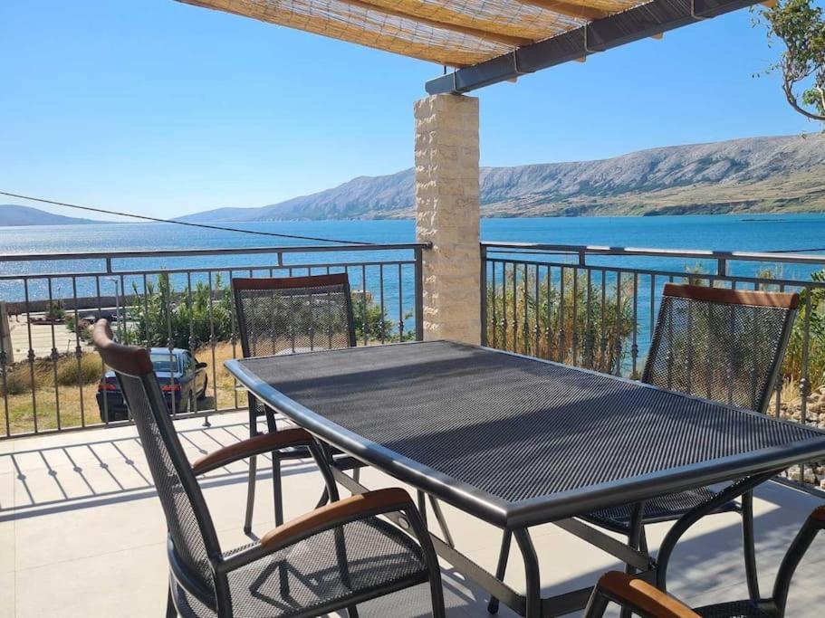 einen Tisch und Stühle auf einem Balkon mit Blick auf das Wasser in der Unterkunft Sea View Apartment - first row to the beach in Zubovići