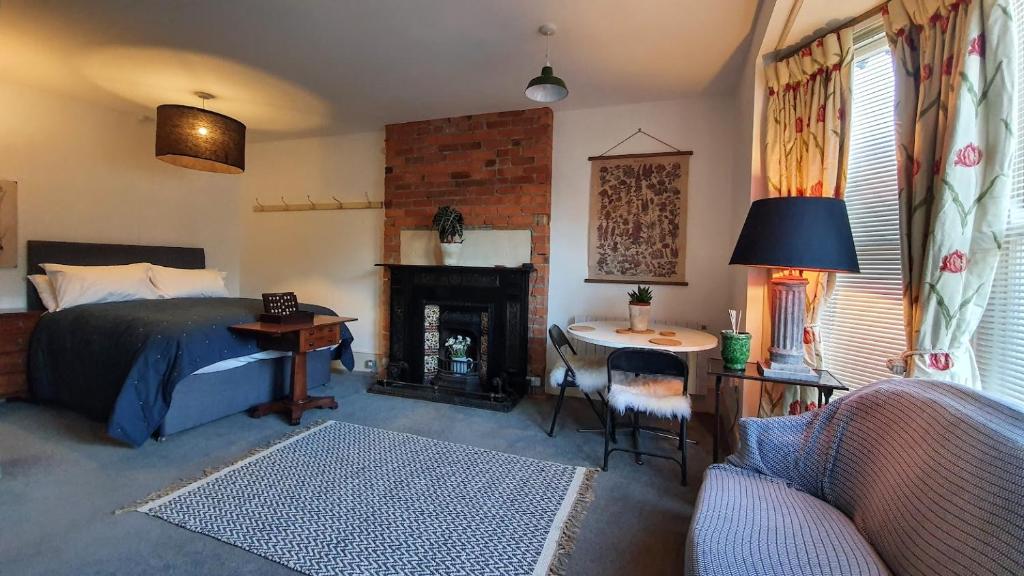 a bedroom with a bed and a desk and a fireplace at Stylish Town Centre Apartments in Nailsworth