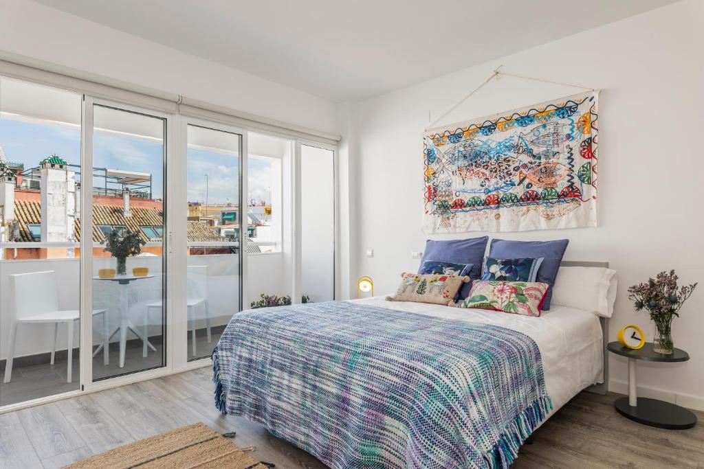 1 dormitorio con 1 cama y balcón con mesa en Pop Art, Apartamento de Diseño en Arenal 303, en Sevilla