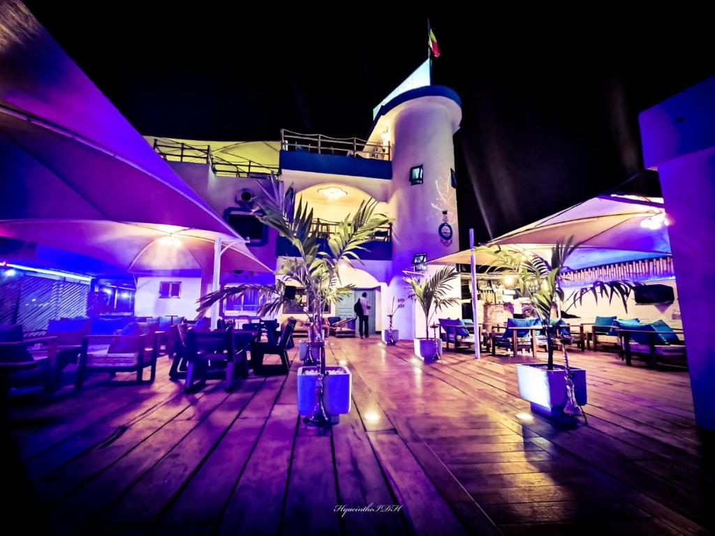 un restaurant avec des tables et des parasols en face d'un bâtiment dans l'établissement Le Hublot, à Cotonou