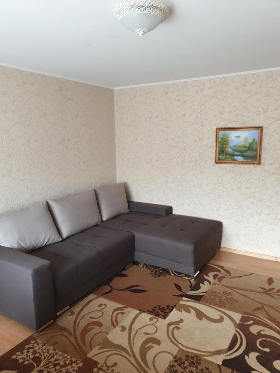 ein Wohnzimmer mit einem schwarzen Sofa und einem Teppich in der Unterkunft Pie jūras in Liepāja
