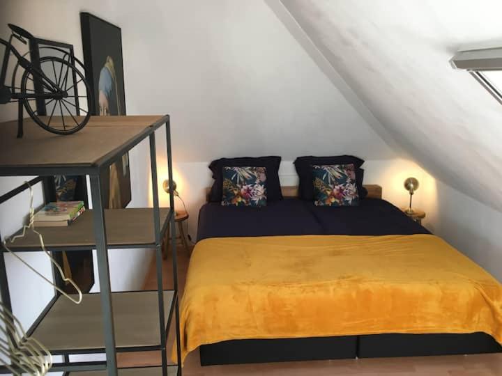 um quarto com uma cama com um cobertor amarelo em Lombok em Westerbork