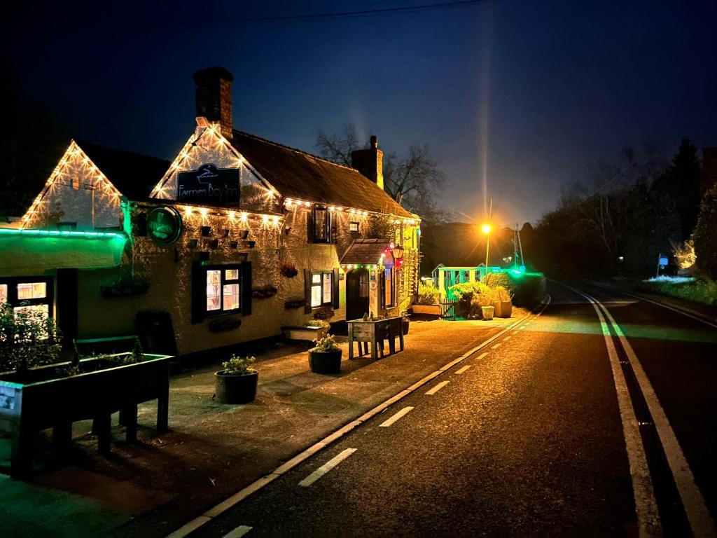a house with christmas lights on a street at night at The Farmers Boy Inn Guest House in Longhope