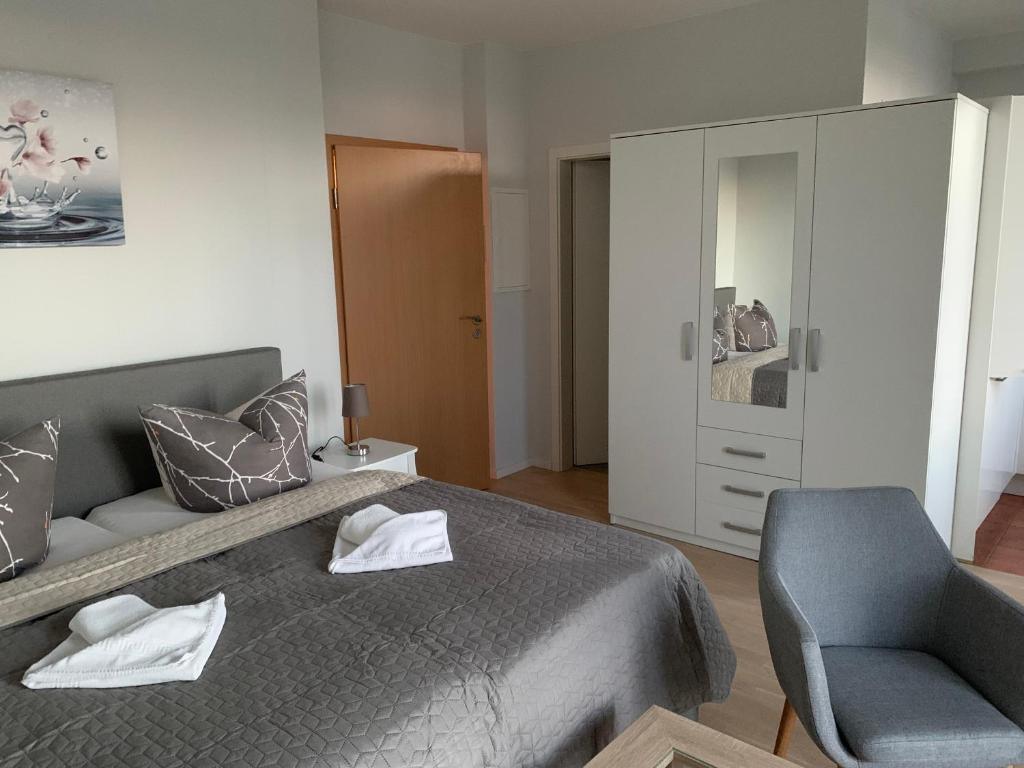 ein Schlafzimmer mit einem grauen Bett und einem Stuhl in der Unterkunft Einraumapartment mit Seeblickbalkon in Rheinsberg