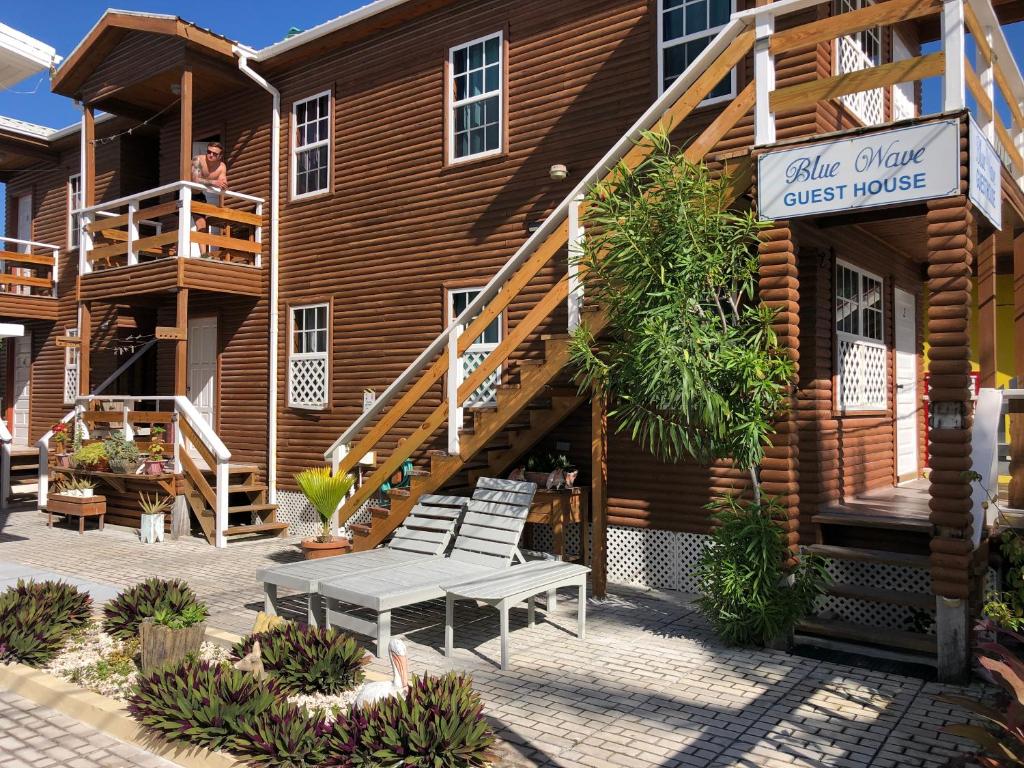 uma casa de madeira com um banco em frente em Blue Wave Guest House em Caye Caulker