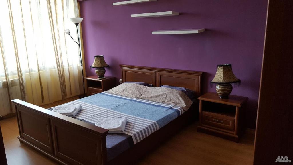 a bedroom with a bed with a purple wall at Апартамент Орхид Хилс in Varna City