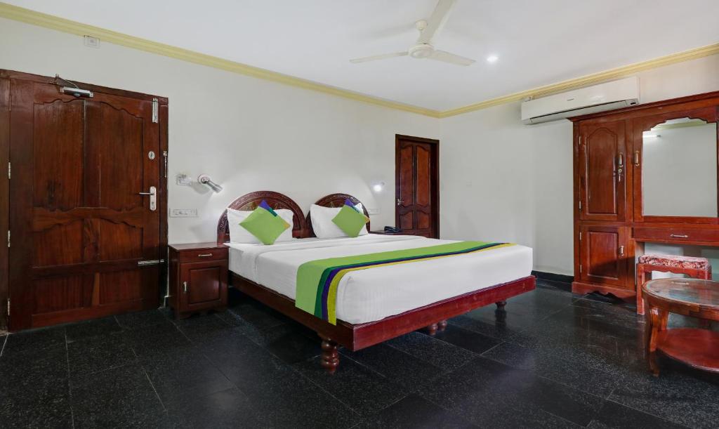 Schlafzimmer mit einem Bett und einem Holzschrank in der Unterkunft Itsy By Treebo - The Waters Edge Beach Resort in Kovalam
