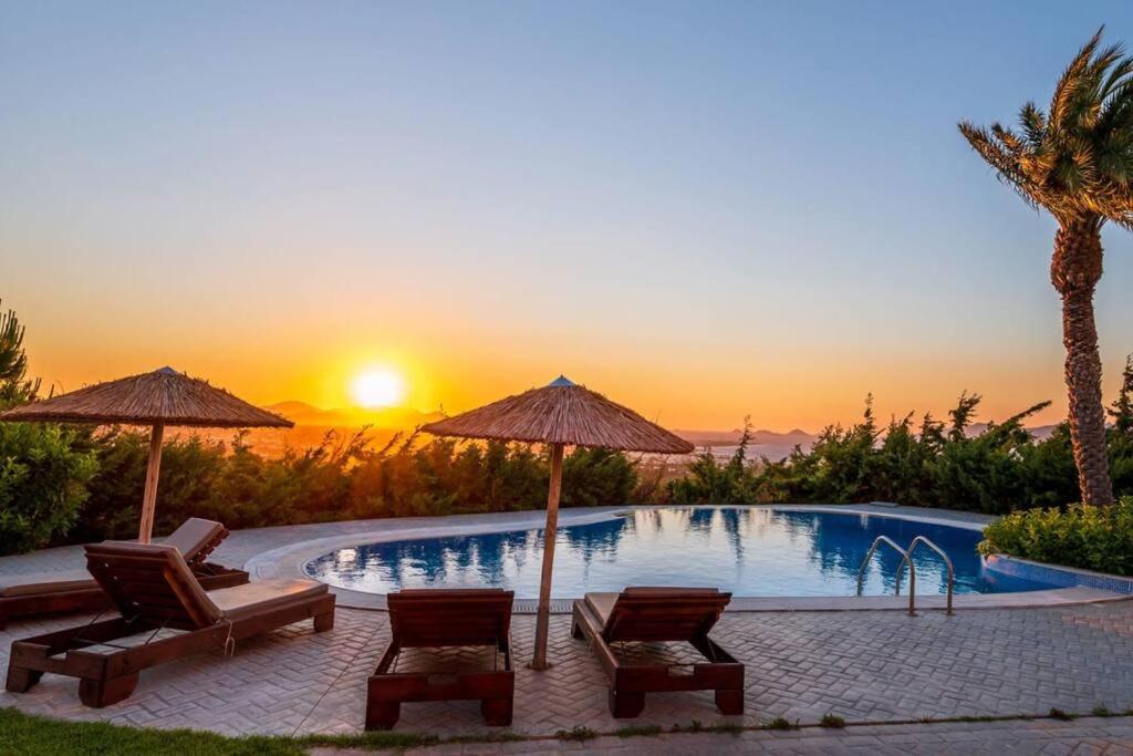 basen z leżakami i parasolami oraz zachodem słońca w obiekcie Breathtaking view guesthouse2 w mieście Psalidi