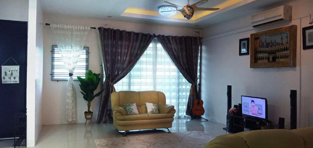 a living room with a chair and a television at 7eVenKitchen Hmestay in Jitra