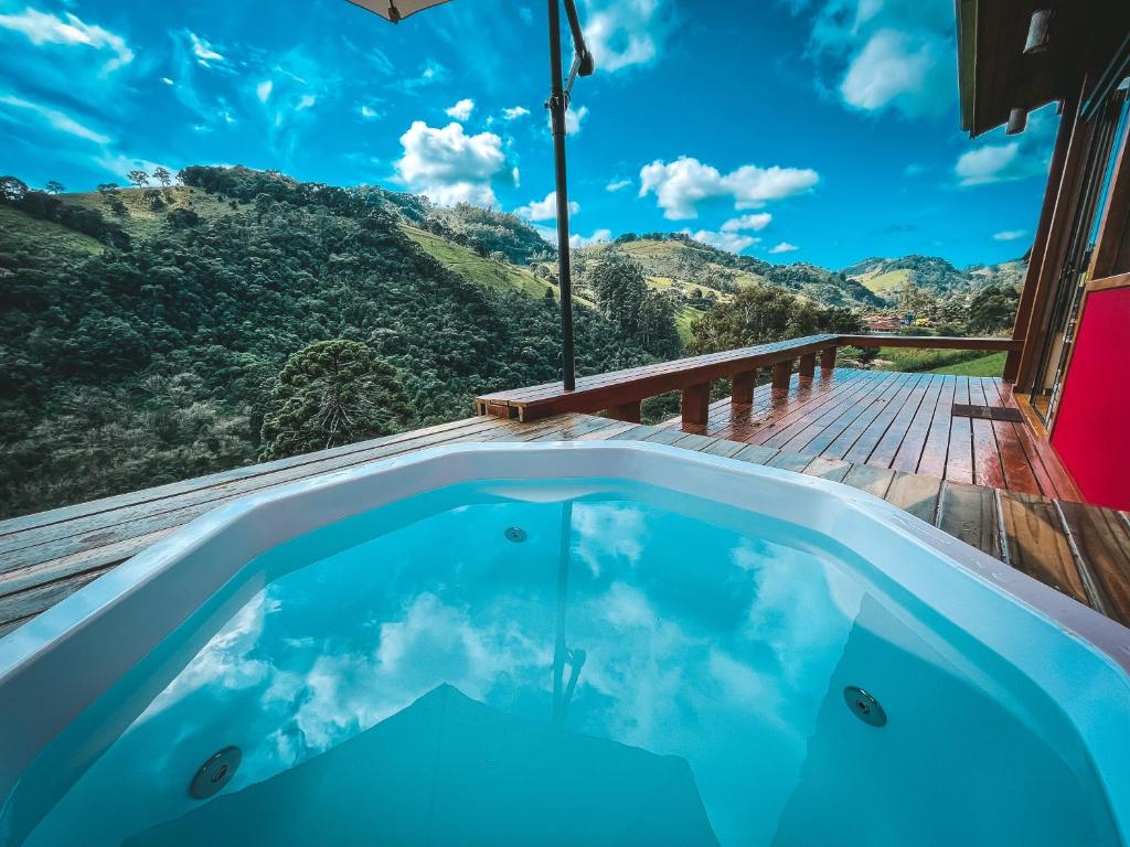 a hot tub on a deck with a view of the mountains at Pousada Espelho Dagua in Gonçalves