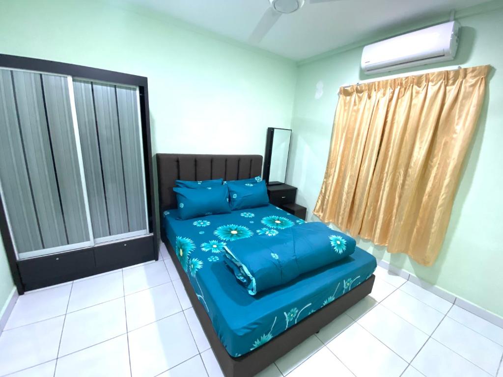 a bedroom with a bed with blue sheets and a window at Green House Homestay in Masjid Tanah