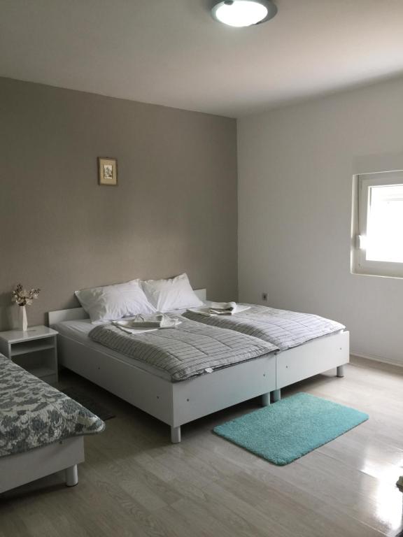 a bedroom with a white bed and a blue rug at Rooms Nikola Rule Ostojic in Međugorje