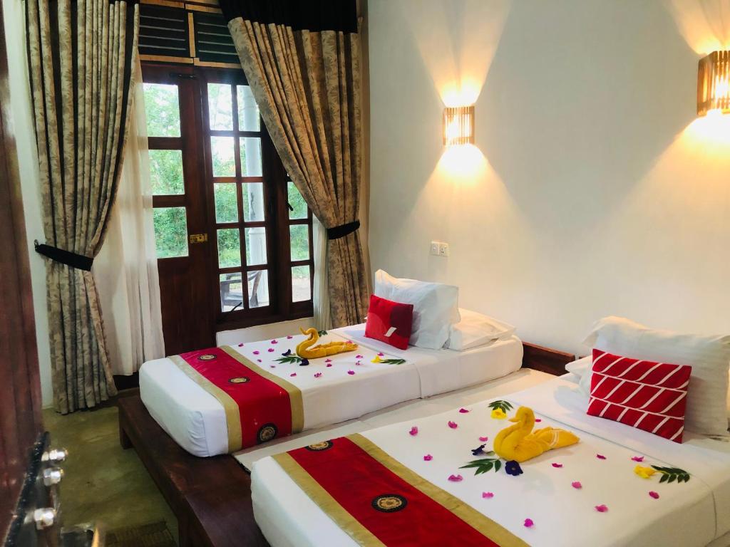 two beds in a room with two bedsitures at Grand freedom in Sigiriya