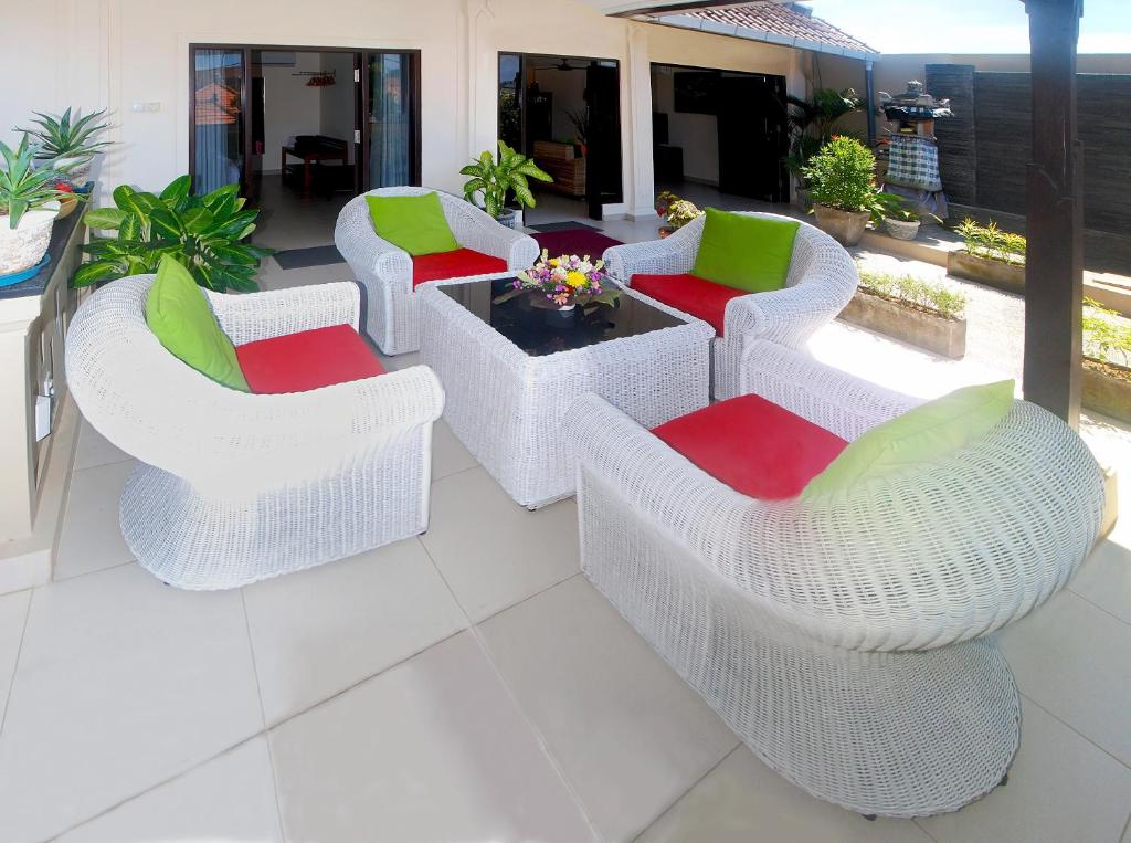 a patio with white wicker chairs and a table at Villa Taluh in Sanur