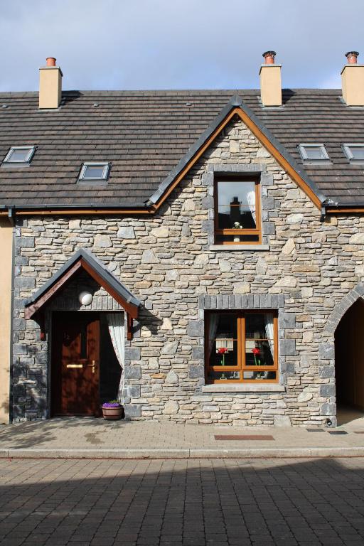 a stone building with two windows on it at Cosy Holidayhomes Kenmare in Kenmare