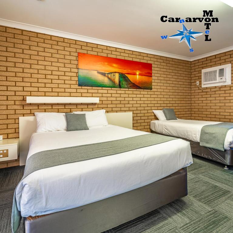 卡那封Carnarvon Motel的一间卧室，有两张床和一堵砖墙