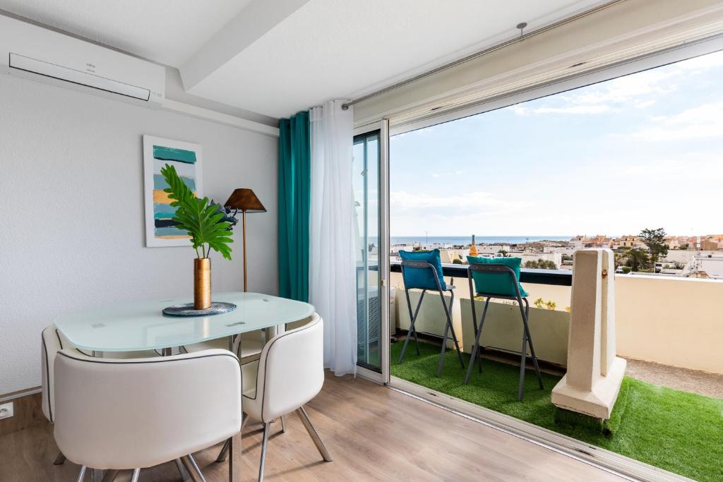 une salle à manger avec une table et des chaises et un balcon dans l'établissement BULLDOG port nature 4 - village naturiste, au Cap d'Agde