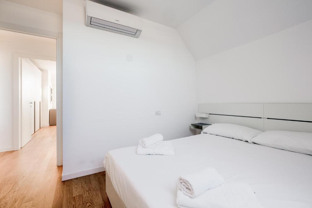 Biała sypialnia z białym łóżkiem i białą ścianą w obiekcie Modern APT with Terrace, WIFI & AC w Mediolanie