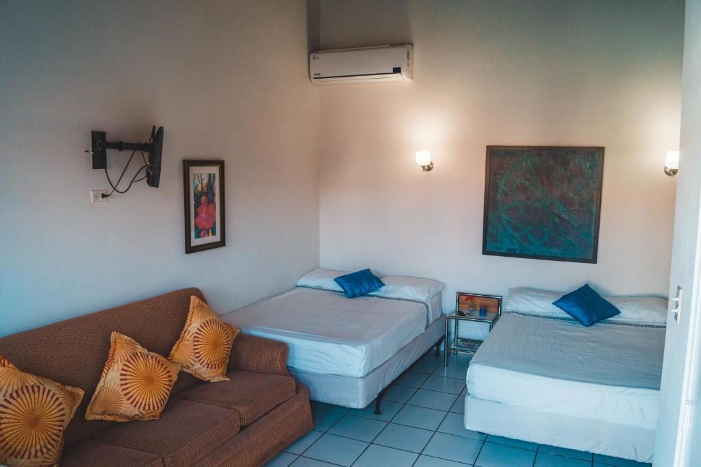a hotel room with two beds and a couch at Courtesy Apartments Aruba in Oranjestad