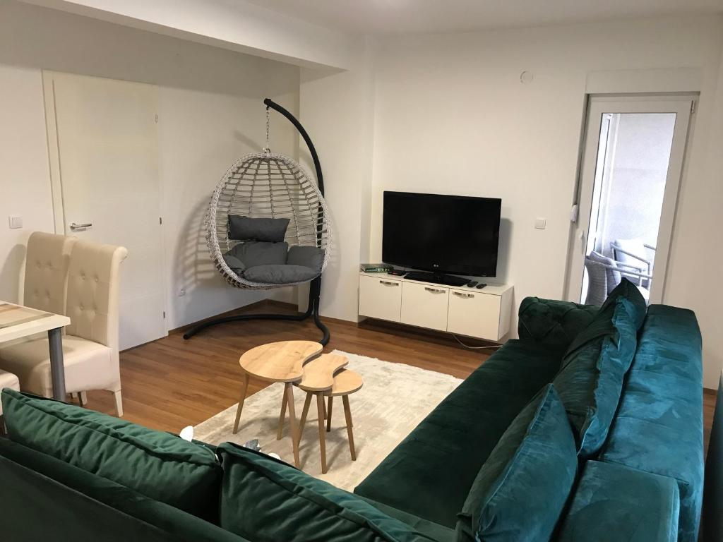 Green Apartment في نوفي بازار: غرفة معيشة مع أريكة خضراء وتلفزيون