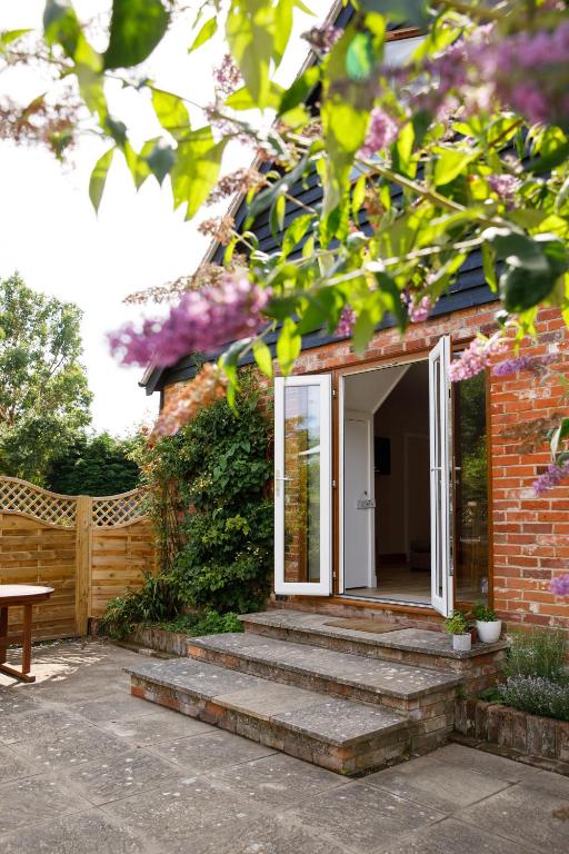 a brick house with stairs leading to a door at Escape to Orchard Croft Lodge, a beautifully appointed dog friendly holiday home with flexible Super King or Twin beds offering the perfect stay for couples families or friends Close to West Wittering Beach Goodwood & Southend Barns in Chichester
