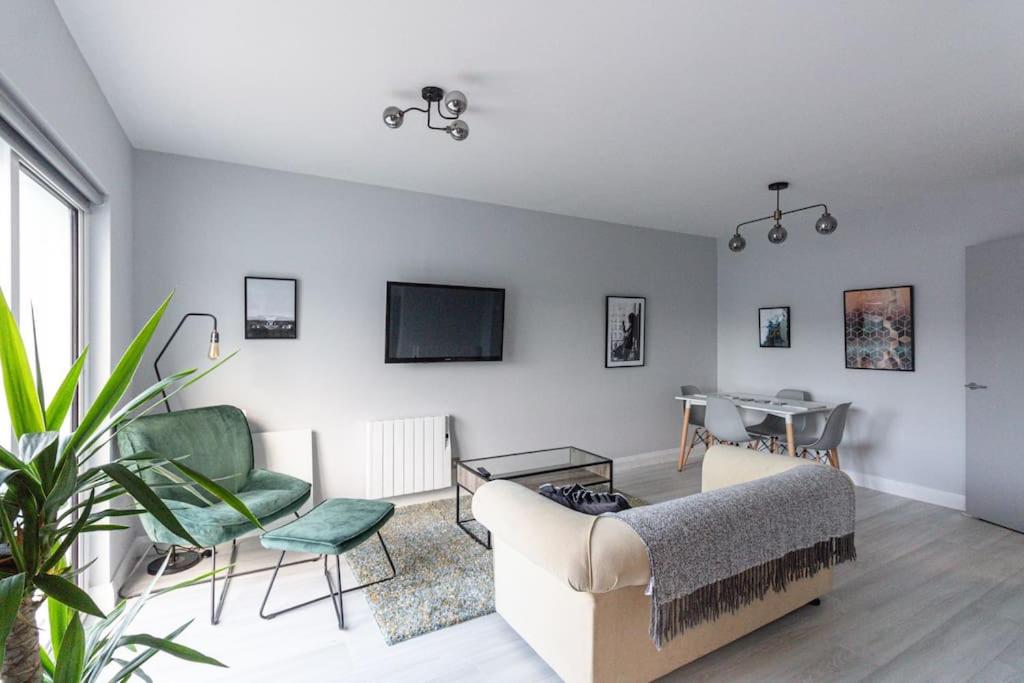 a living room with a couch and chairs and a tv at Causeway Coast Beach Front Apartment - Ballycastle in Ballycastle
