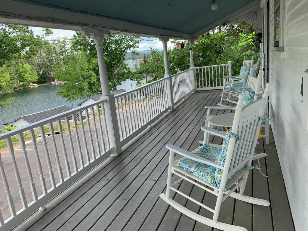 - une terrasse couverte avec des fauteuils à bascule et une vue sur l'eau dans l'établissement Winnisquam Lake House, à Tilton