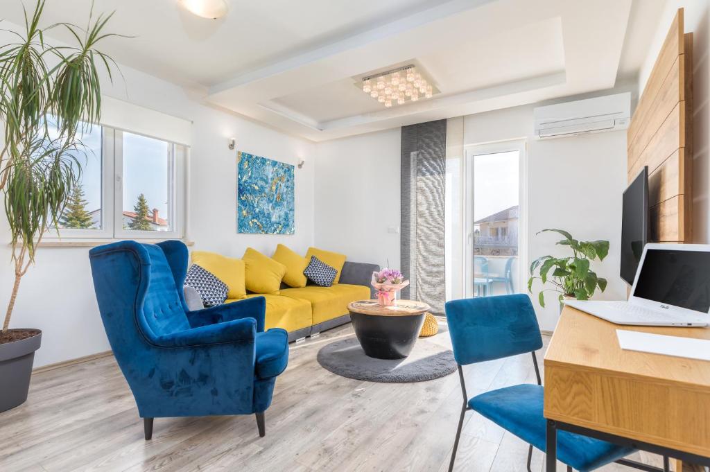 een woonkamer met blauwe stoelen en een gele bank bij Apartman Nina in Fažana