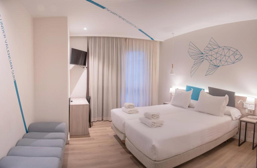 a bedroom with a large white bed and a chair at Hotel Mediterraneo Valencia in Valencia
