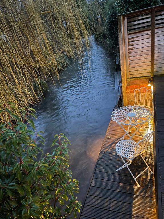 2 chaises et une table sur un quai dans l'eau dans l'établissement Maya residence, à Bourne End