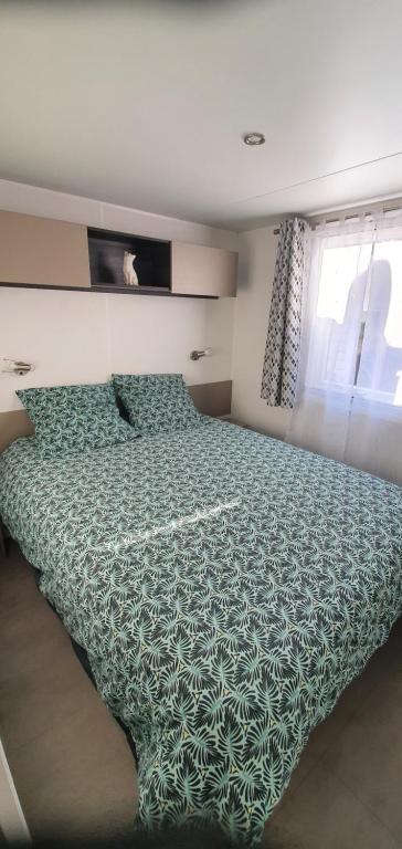 - une chambre avec un lit doté d'une couette verte et d'une fenêtre dans l'établissement MH 149 4 pers camping Bois Dormant confort et détente, à Saint-Jean-de-Monts