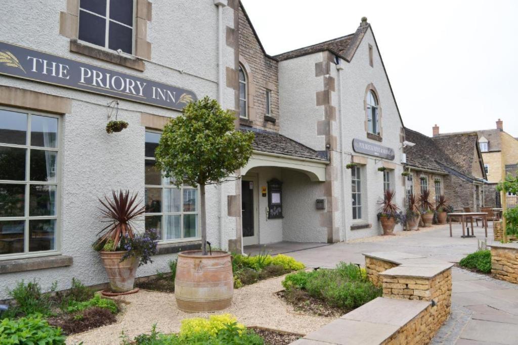 a building with a sign that reads the priory inn at Priory Inn in Tetbury