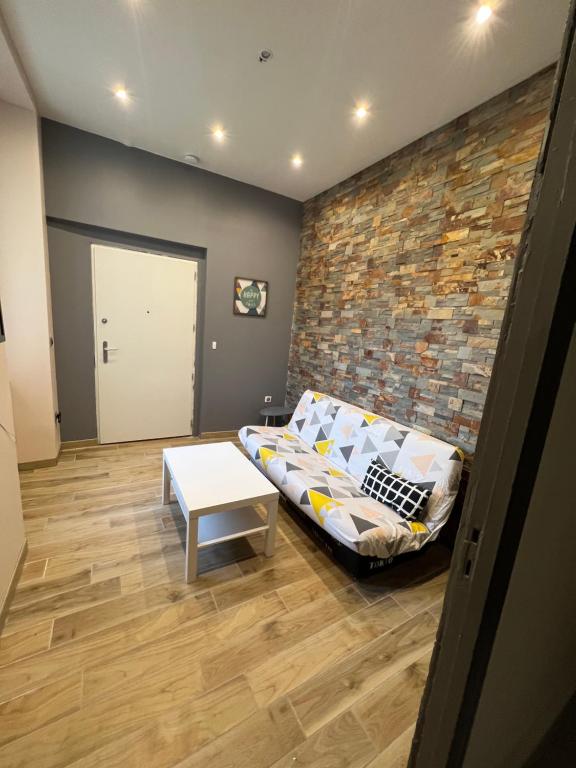 ein Wohnzimmer mit Sofa und Ziegelwand in der Unterkunft L’ÉMERAUDE 3 in Châlons-en-Champagne