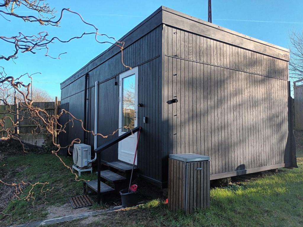 a black tiny house with a staircase in a yard at Bonjour Copenhagen in Herlev