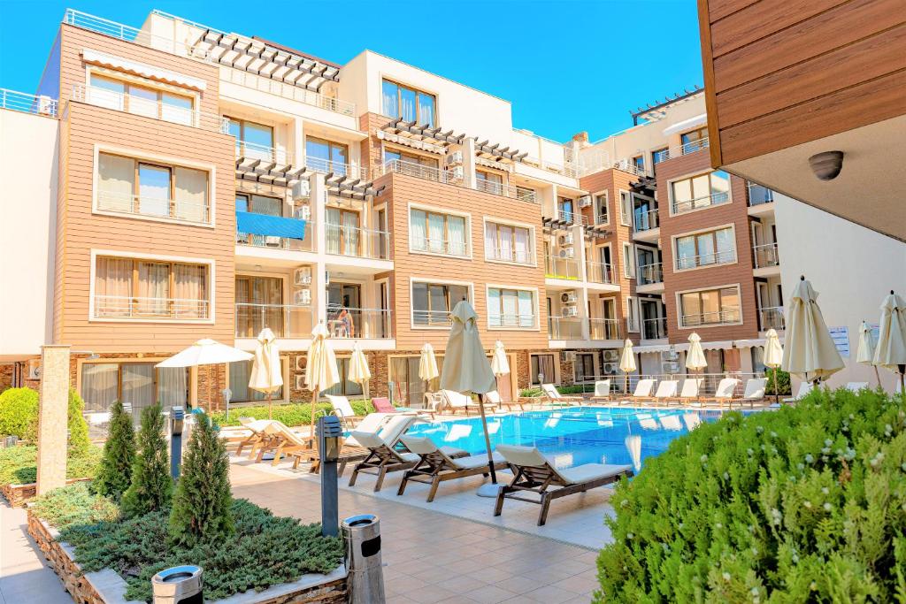 uma piscina num hotel com cadeiras e guarda-sóis em Menada Horyzont Apartments em Sozopol