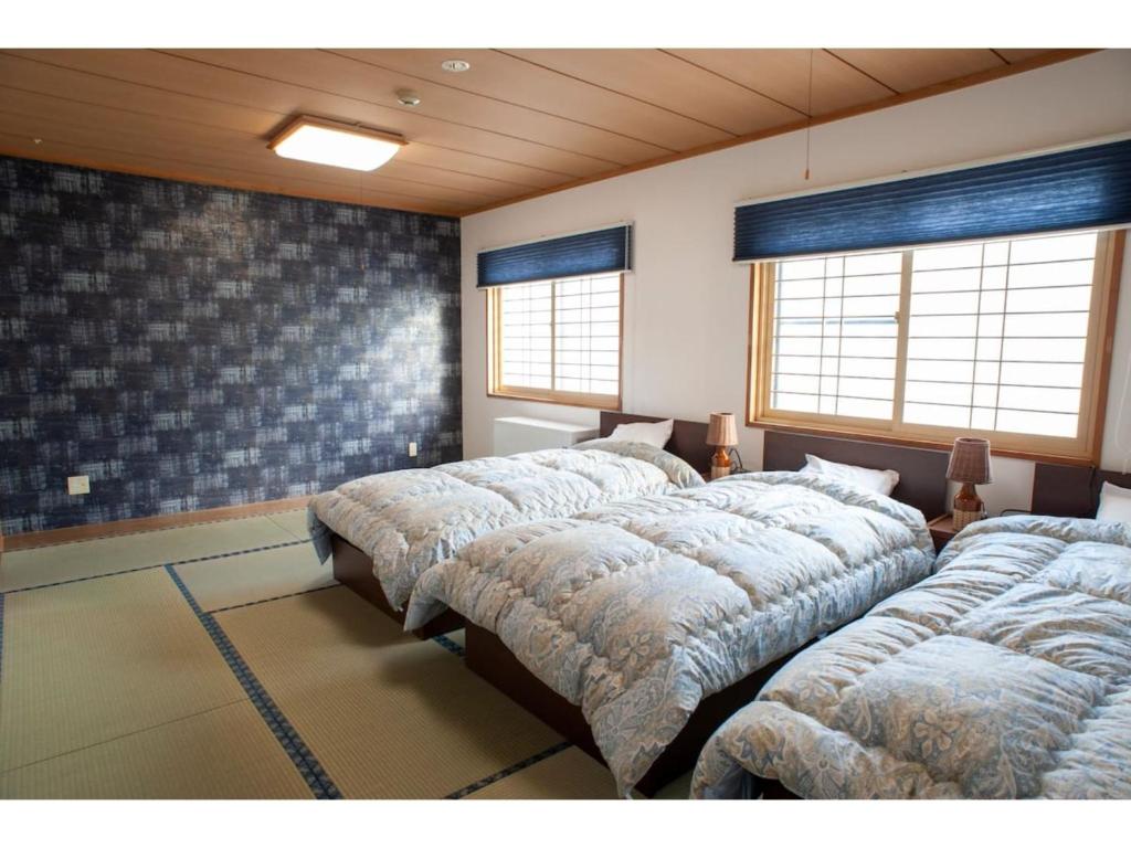 szereg łóżek w pokoju z oknami w obiekcie Guest House Tou - Vacation STAY 26345v w mieście Kushiro