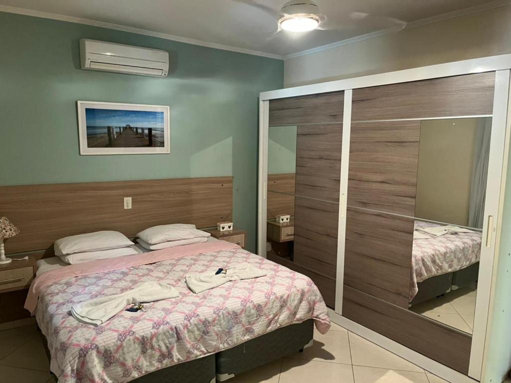 Hotel Vitória في Pedreira: غرفة نوم بسرير ومرآة كبيرة