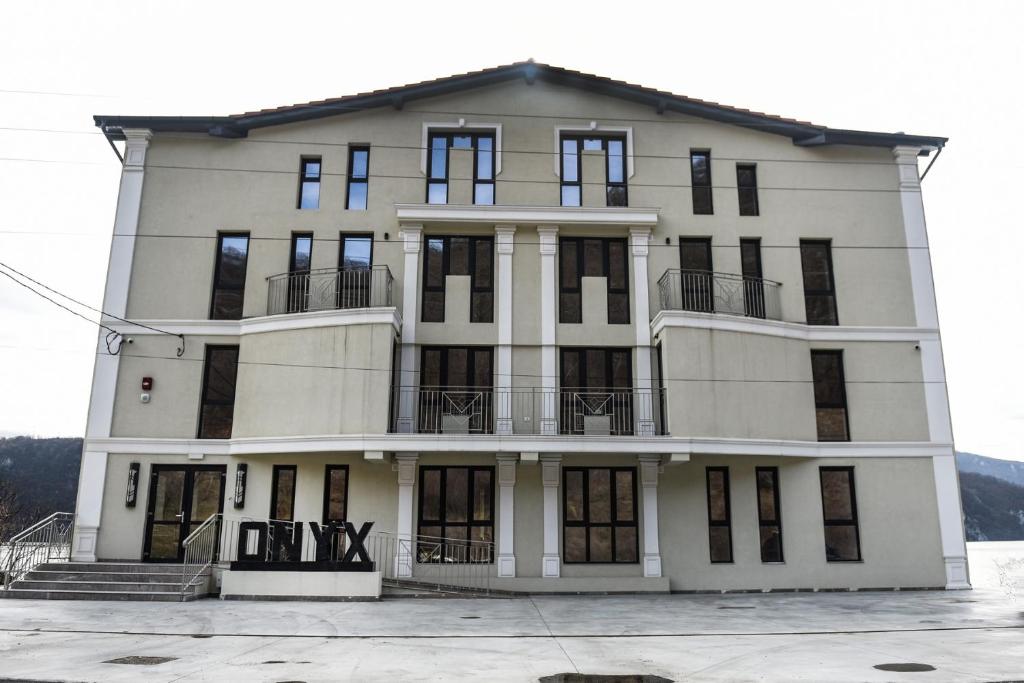 un gran edificio blanco con ventanas y balcones en Pensiunea Onyx en Eşelniţa