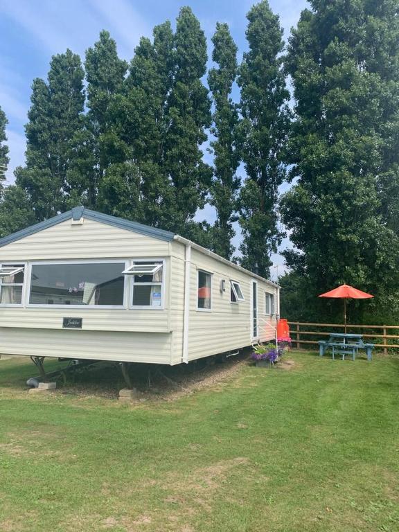 a white rv parked in a field next to trees at DaisyChain 2 Getaways - The perfect place to Stay - Play - Getaway in East Mersea
