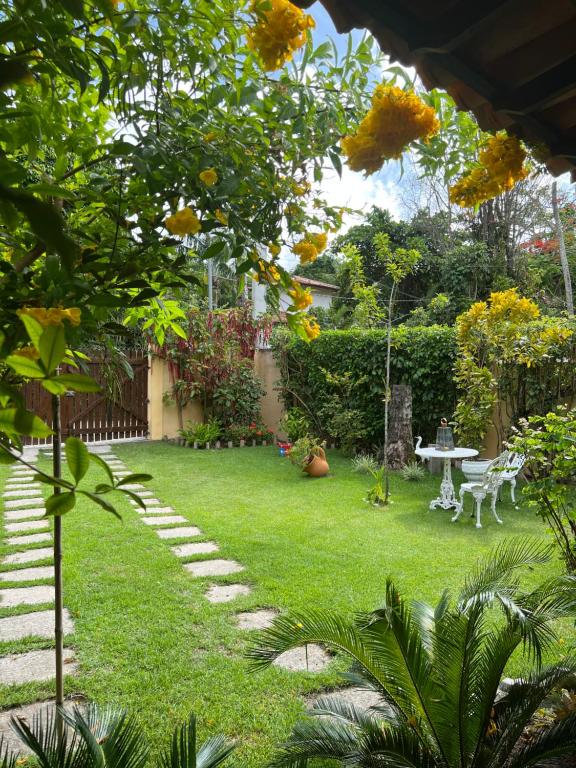 un giardino con prato, tavolo e sedie di Casa Vila Tortuga a Arraial d'Ajuda