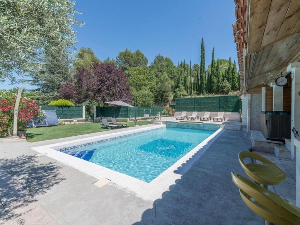 a swimming pool with chairs next to a house at Superb house with pool near the Luberon in Oppède