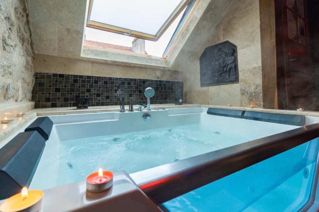 een groot bad met twee kaarsen erin bij SOUS MON TOI Topdestination-Dijon - Sauna & jacuzzi - Classé 3 étoiles in Dijon