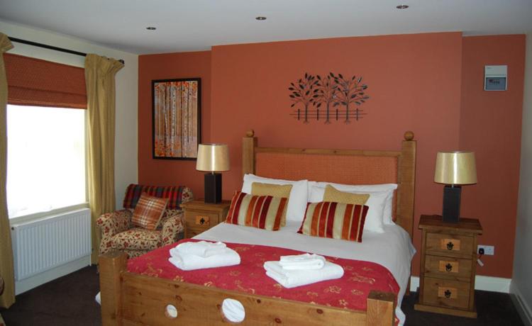a bedroom with a large bed with red walls at The Barrington Arms Hotel in Shrivenham