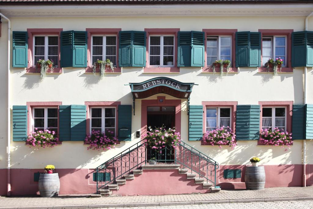 a building with pink and green shuttered windows and stairs at Landgasthof Rebstock in Sulzburg